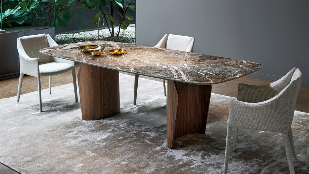 Mesa de comedor rústica de mármol con sillas de mimbre en un patio, vista desde arriba.