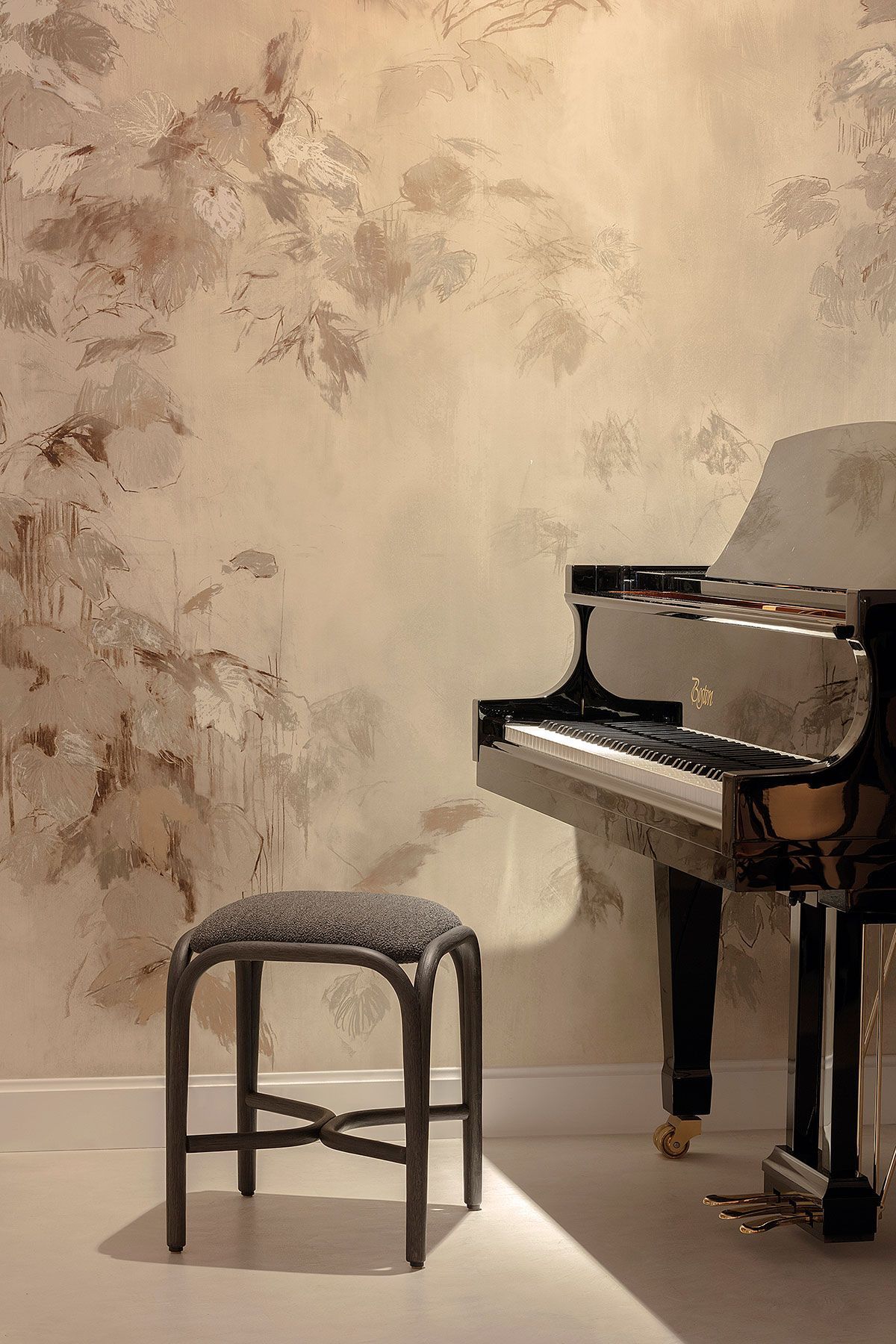 Un piano y un taburete tapizado en una habitación con iluminación tenue y papel pintado texturizado de color beige.