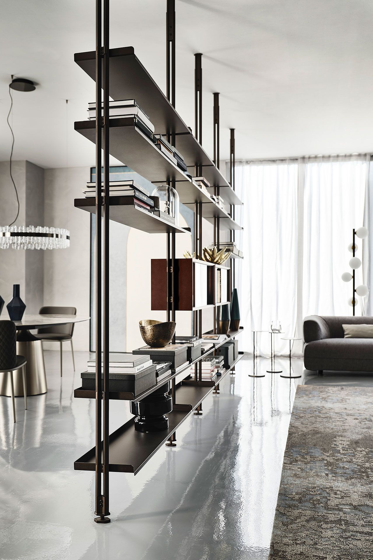 Sala de estar moderna con mampara de cristal, estantes flotantes, sofá y cortinas transparentes.