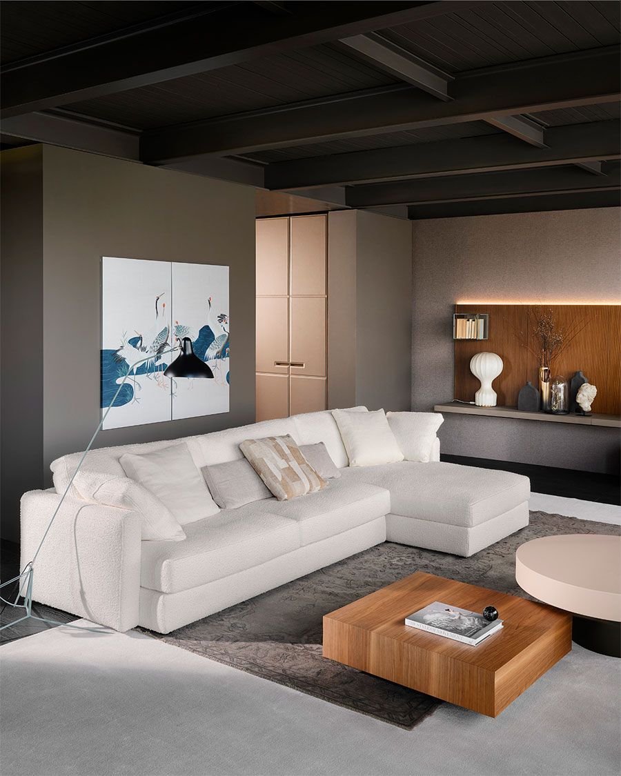 Sala de estar moderna con sofá seccional blanco, mesa de centro de madera, arte abstracto y detalles en madera cálida.