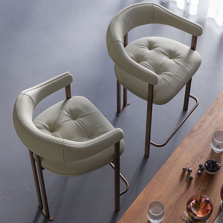 Dos sillas tapizadas de color verde claro junto a una mesa de madera en una habitación luminosa.