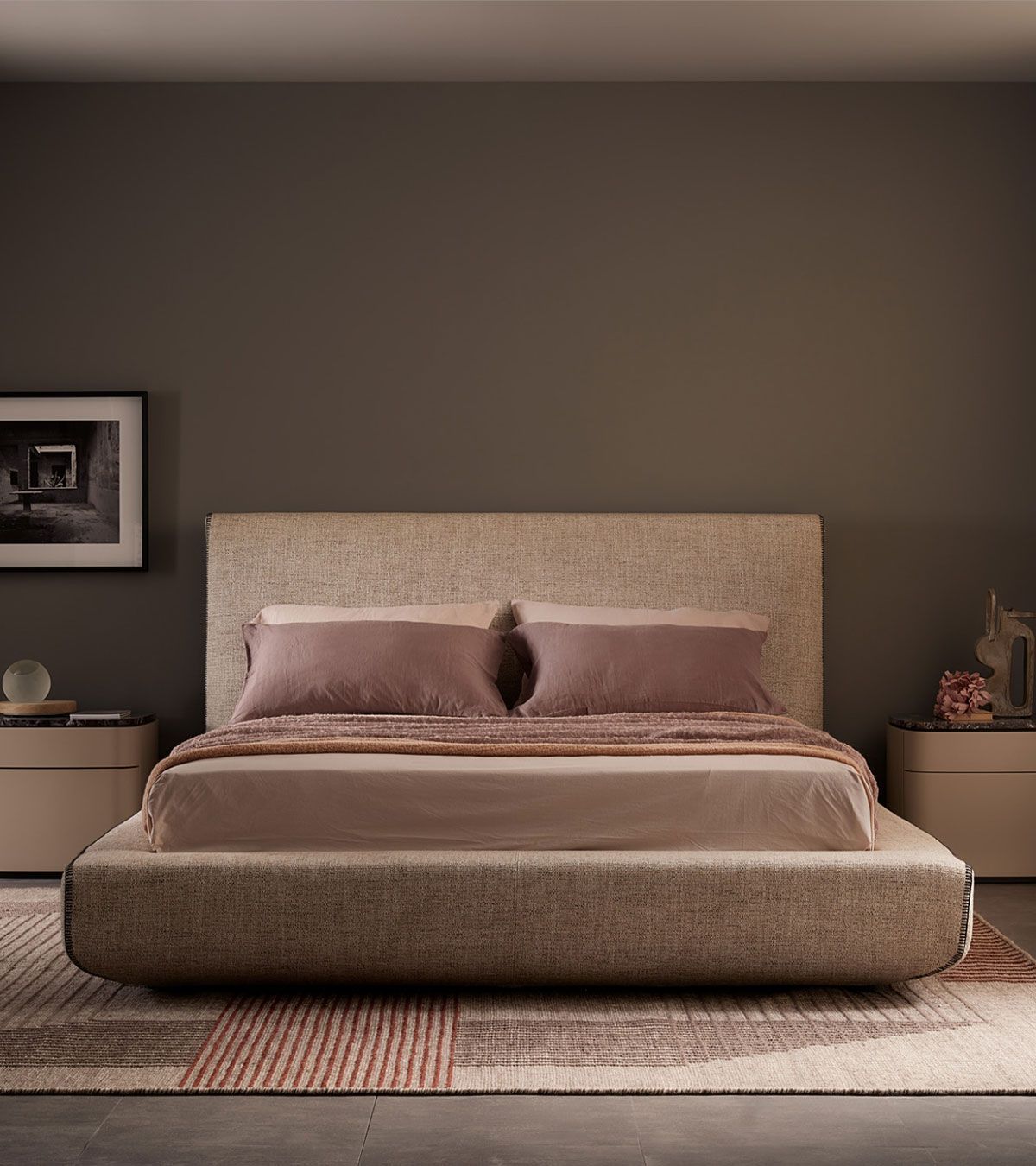 Dormitorio moderno con cama tapizada en color beige, ropa de cama rosa pálido y decoración cálida en tonos neutros.