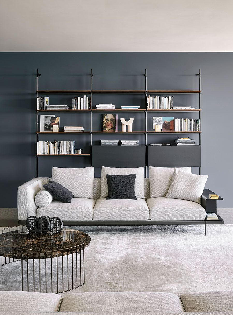 Sala de estar moderna con un sofá claro, estanterías negras llenas de libros