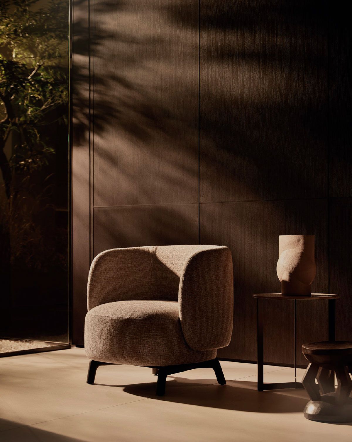 Un cómodo sillón marrón junto a una pequeña mesa auxiliar en una habitación moderna y luminosa