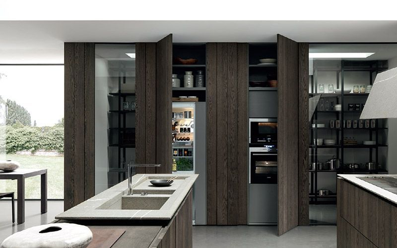 Cocina moderna con gabinetes de madera oscura, fregadero tipo isla y grandes ventanales con vista a un jardín.