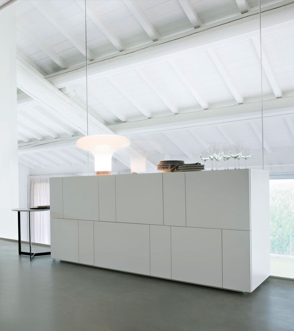 Interior minimalista blanco con un largo armario blanco bajo claraboyas luminosas.