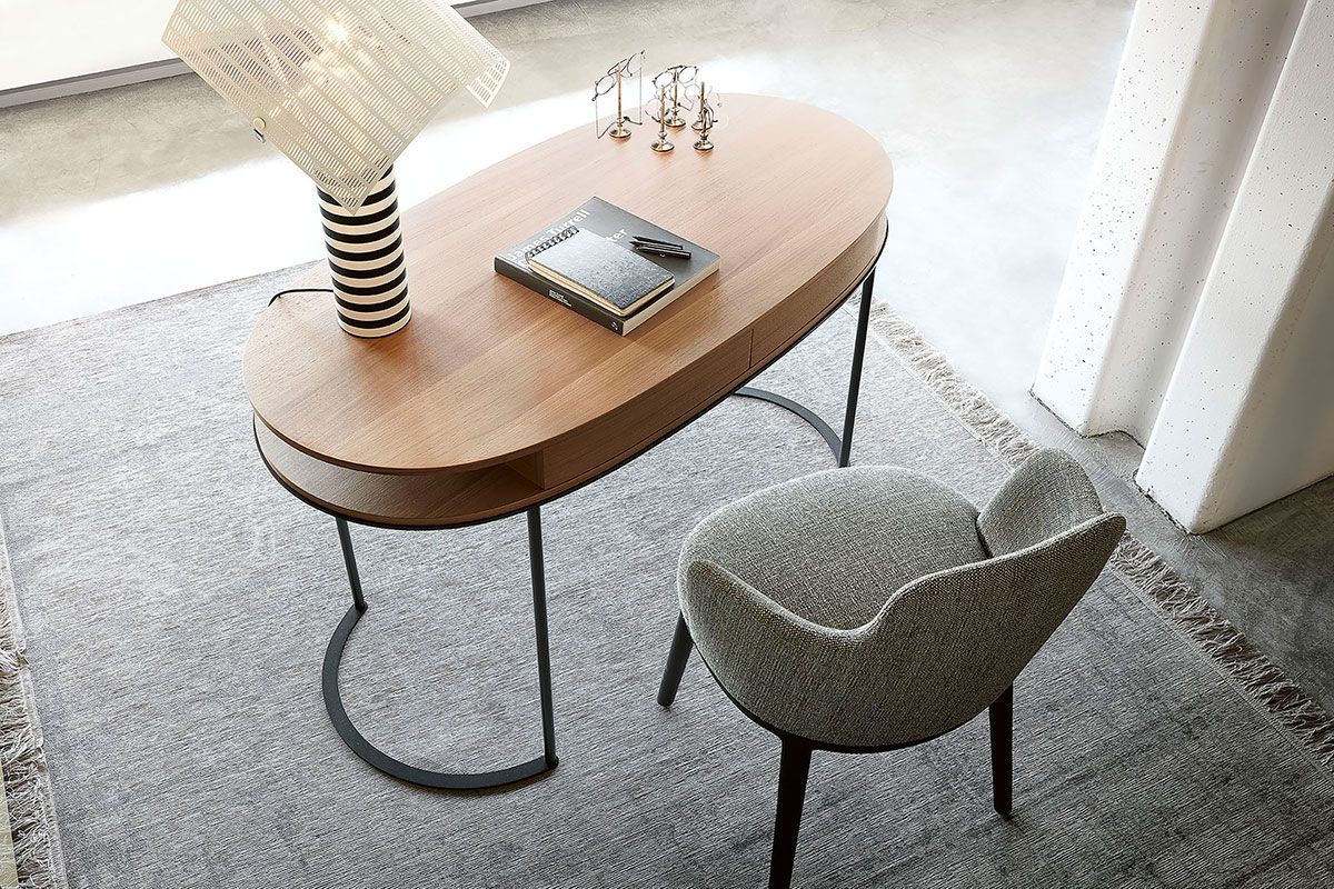 Espacio de trabajo acogedor con un escritorio curvo de madera, silla gris, lámpara, cuaderno y cortinas brillantes