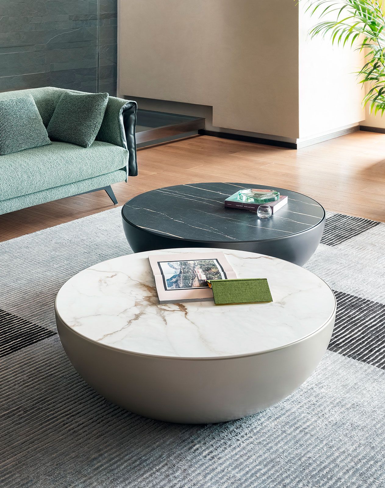 Sala de estar moderna con sofá verde y dos mesas de centro redondas sobre una alfombra gris.