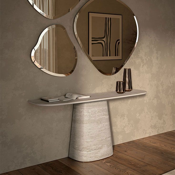 Mesa consola moderna con espejo escultural encima en una habitación de tonos neutros.