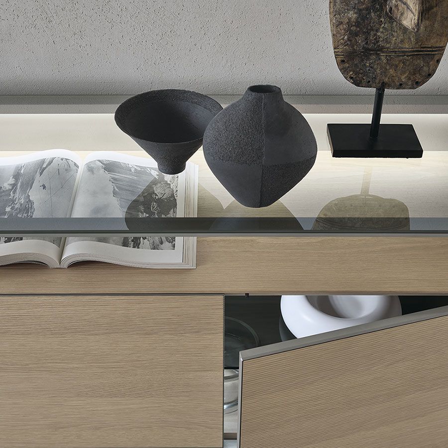 Estantería moderna con jarrones negros, libro abierto y armario color canela en una habitación minimalista.