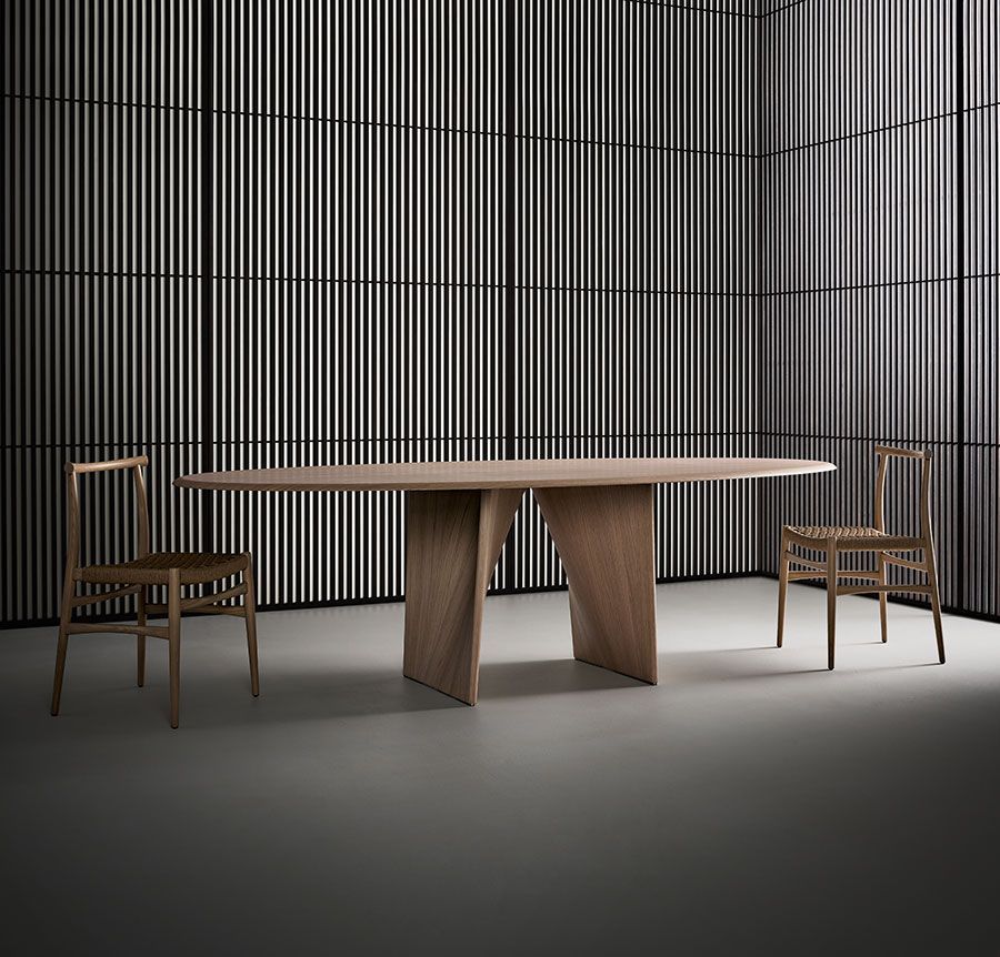 Mesa de comedor minimalista con dos sillas de madera en un estudio de tonos grises.