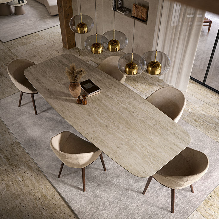 Comedor moderno con mesa de madera clara, sillas beige y lámparas colgantes doradas.