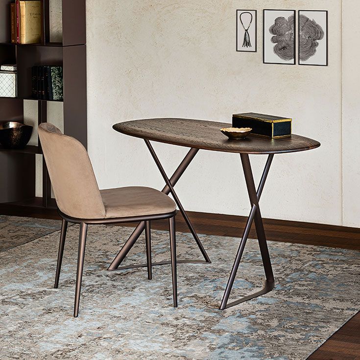 Mesa redonda pequeña y silla beige sobre una alfombra estampada en una habitación minimalista.