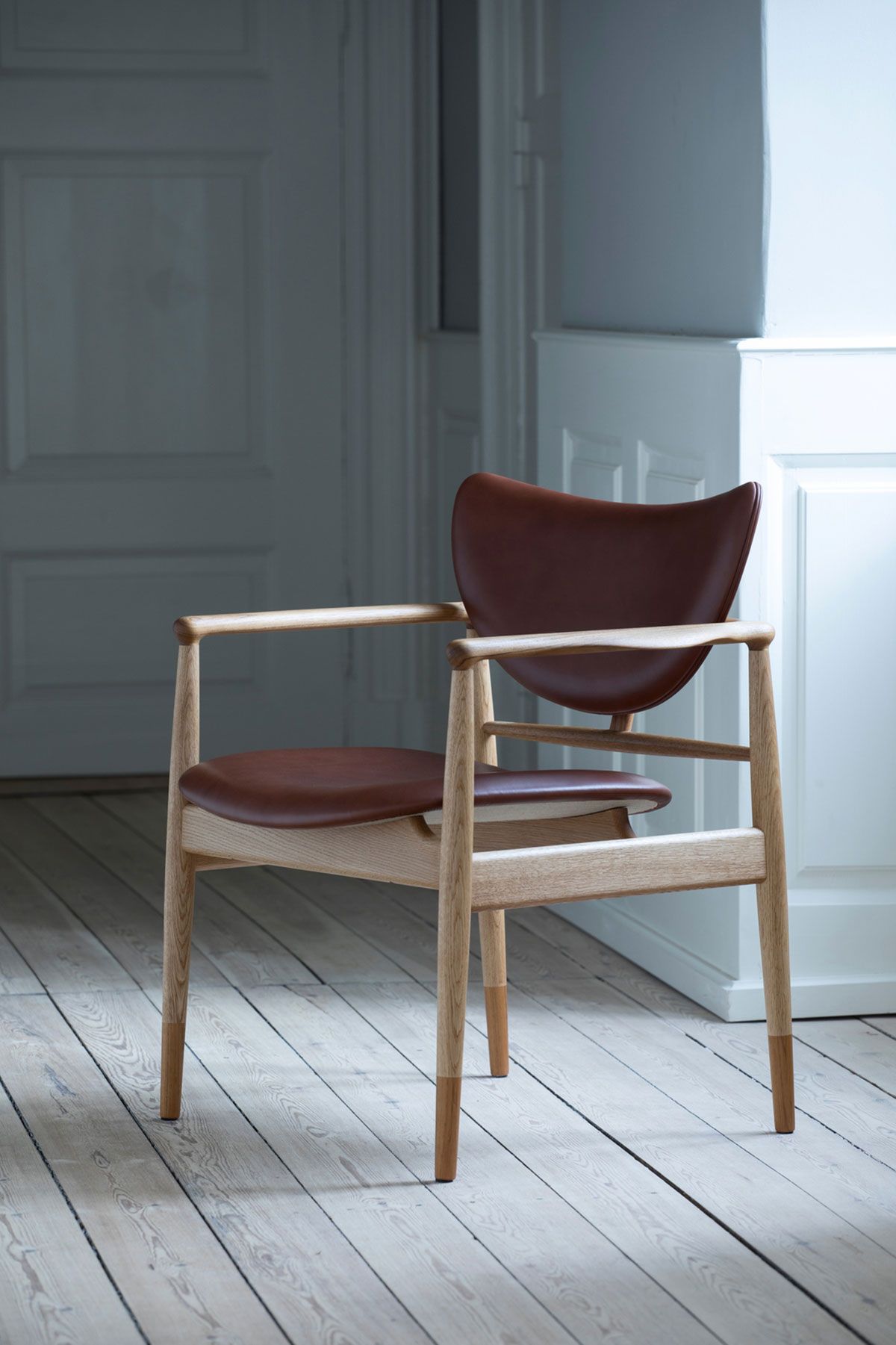 Silla de madera con cojín rojo en una habitación blanca y luminosa.
