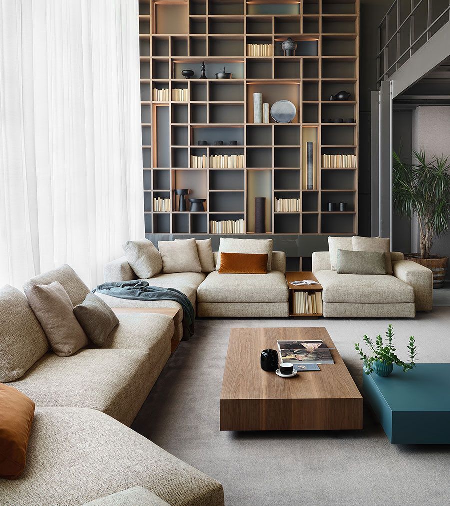 Sala de estar moderna con sofás beige, mesa de centro de madera y estanterías altas empotradas contra la pared.