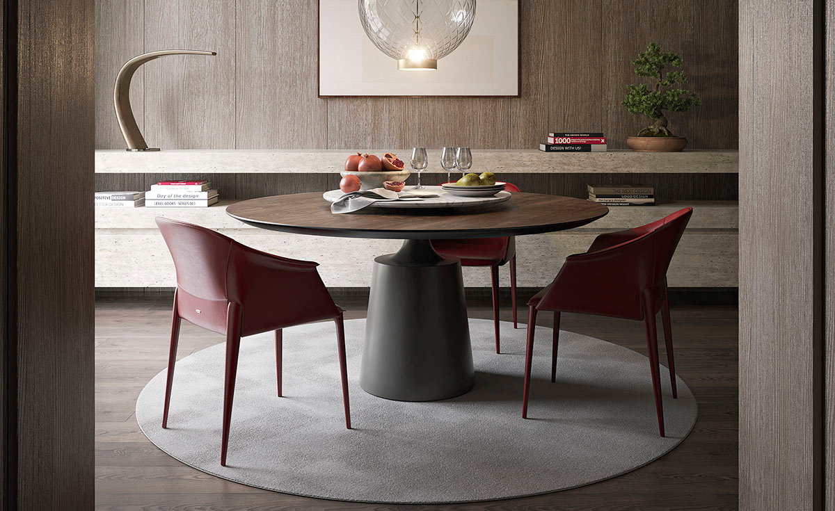 Comedor moderno con mesa redonda, sillas color burdeos y decoración minimalista sobre una alfombra circular.