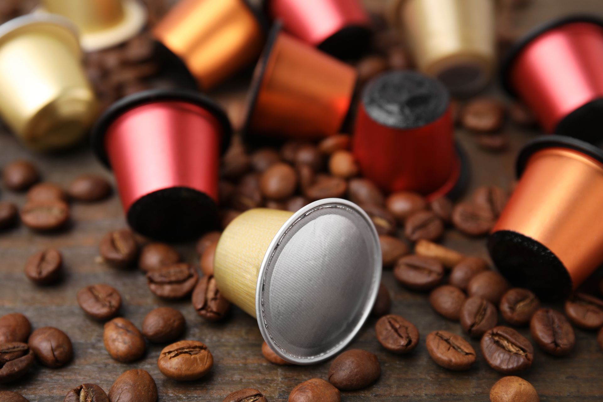Una pila di capsule di caffè e chicchi di caffè su un tavolo di legno.