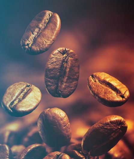 I chicchi di caffè cadono in un mucchio di chicchi di caffè.