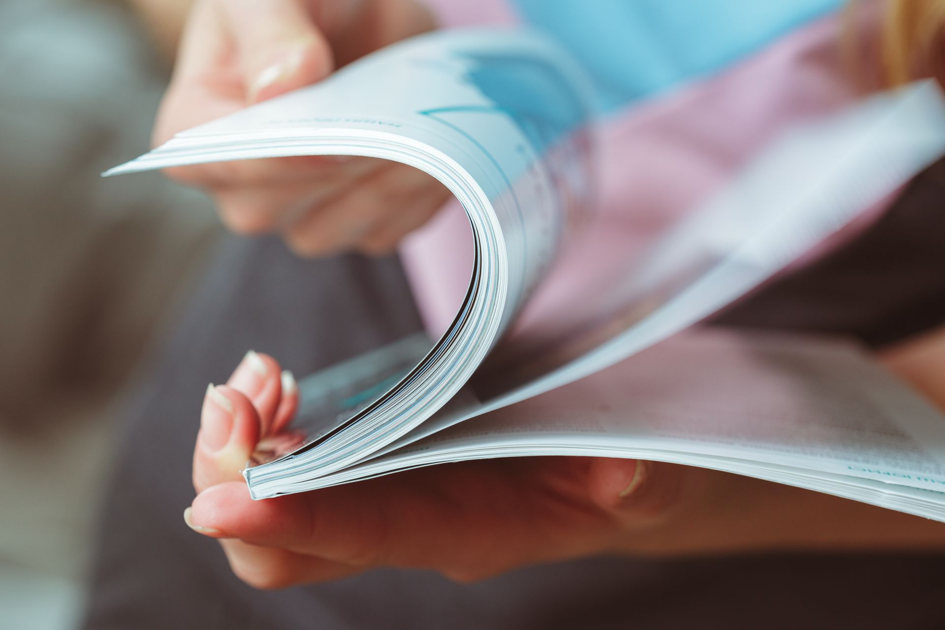 Hände blättern die Seiten einer Zeitschrift um und zeigen Druck und Farben.