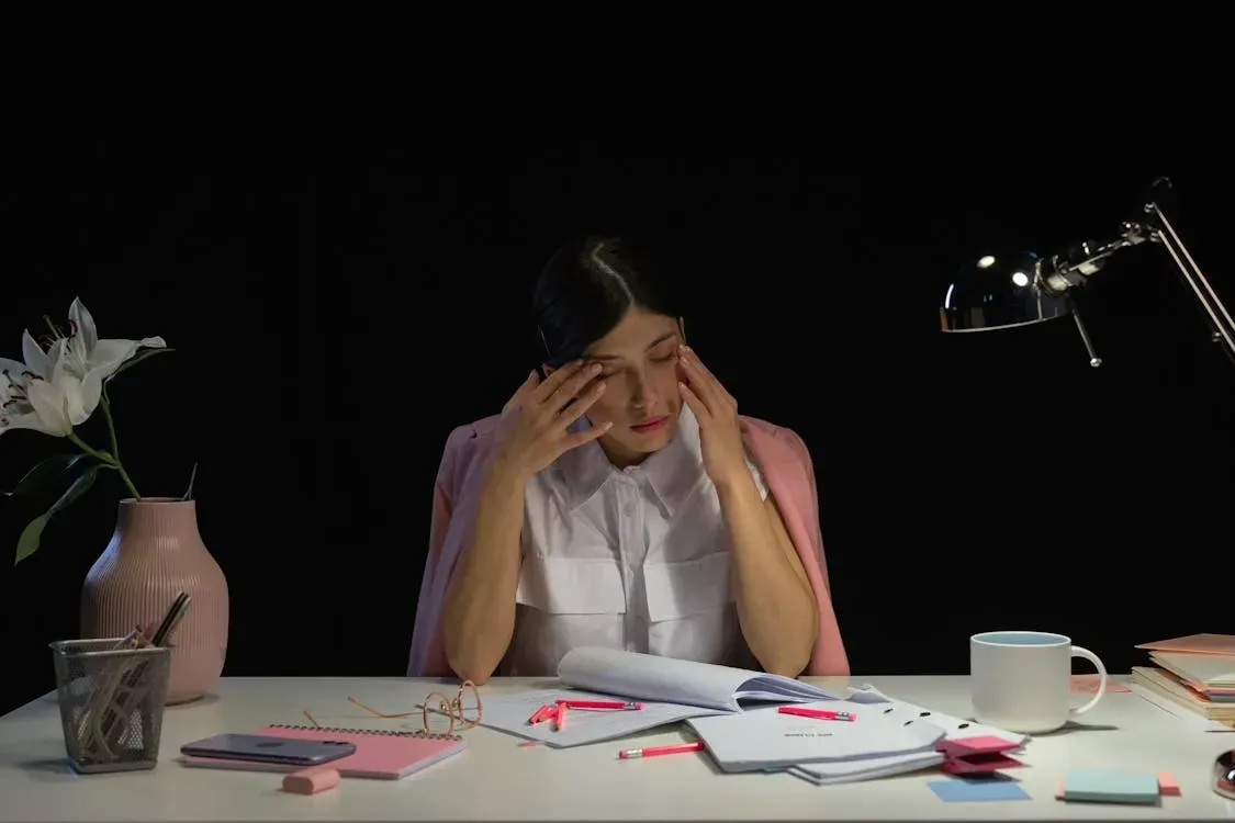 Tired employee sitting at an office desk, looking exhausted and disengaged after long working hours.