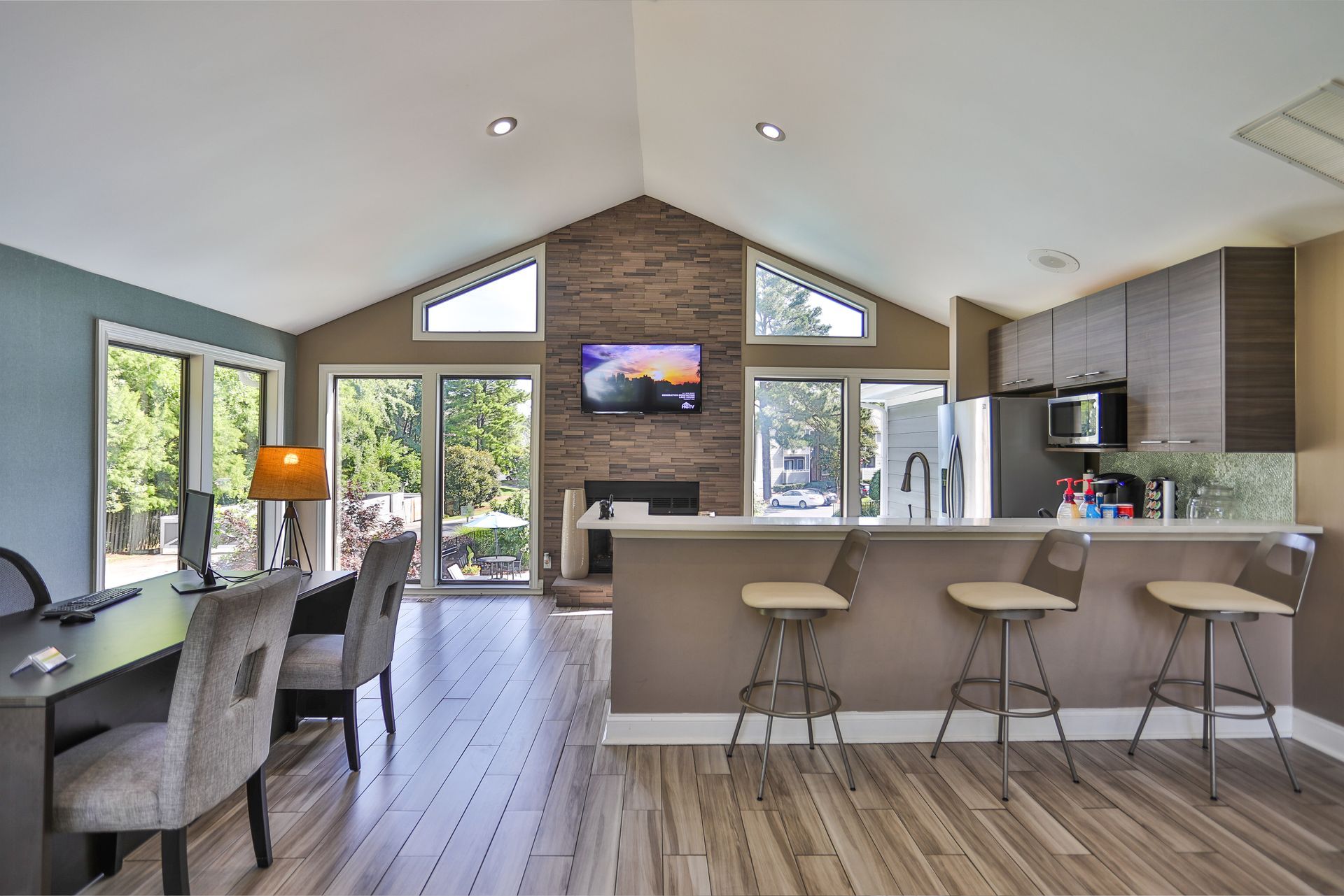 Open-plan kitchen and dining area with a vaulted ceiling, large windows, gray chairs, and a breakfast bar at Aurea Station Apartments in South Charlotte, NC.
