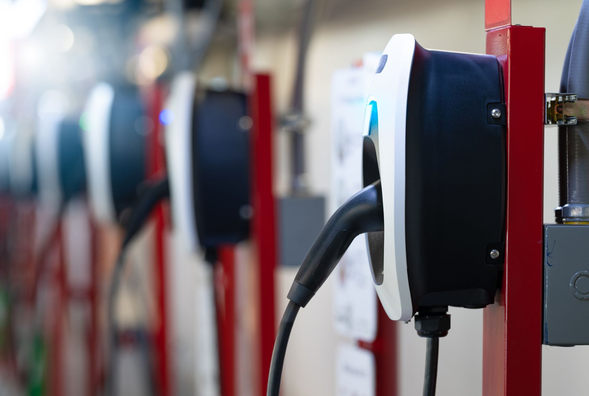 Row of electric vehicle charging stations with cables in a garage-like setting