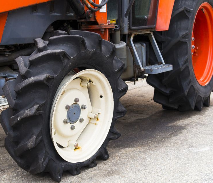 Orange tractor with a large black tire and a white wheel.  Jakes Tyres in South Murwillumbah, NSW