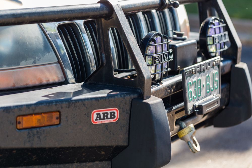 Close-up of a black off-road bumper on a vehicle with the ARB logo, a license plate, and two lights. — Jakes Tyres in South Murwillumbah, NSW