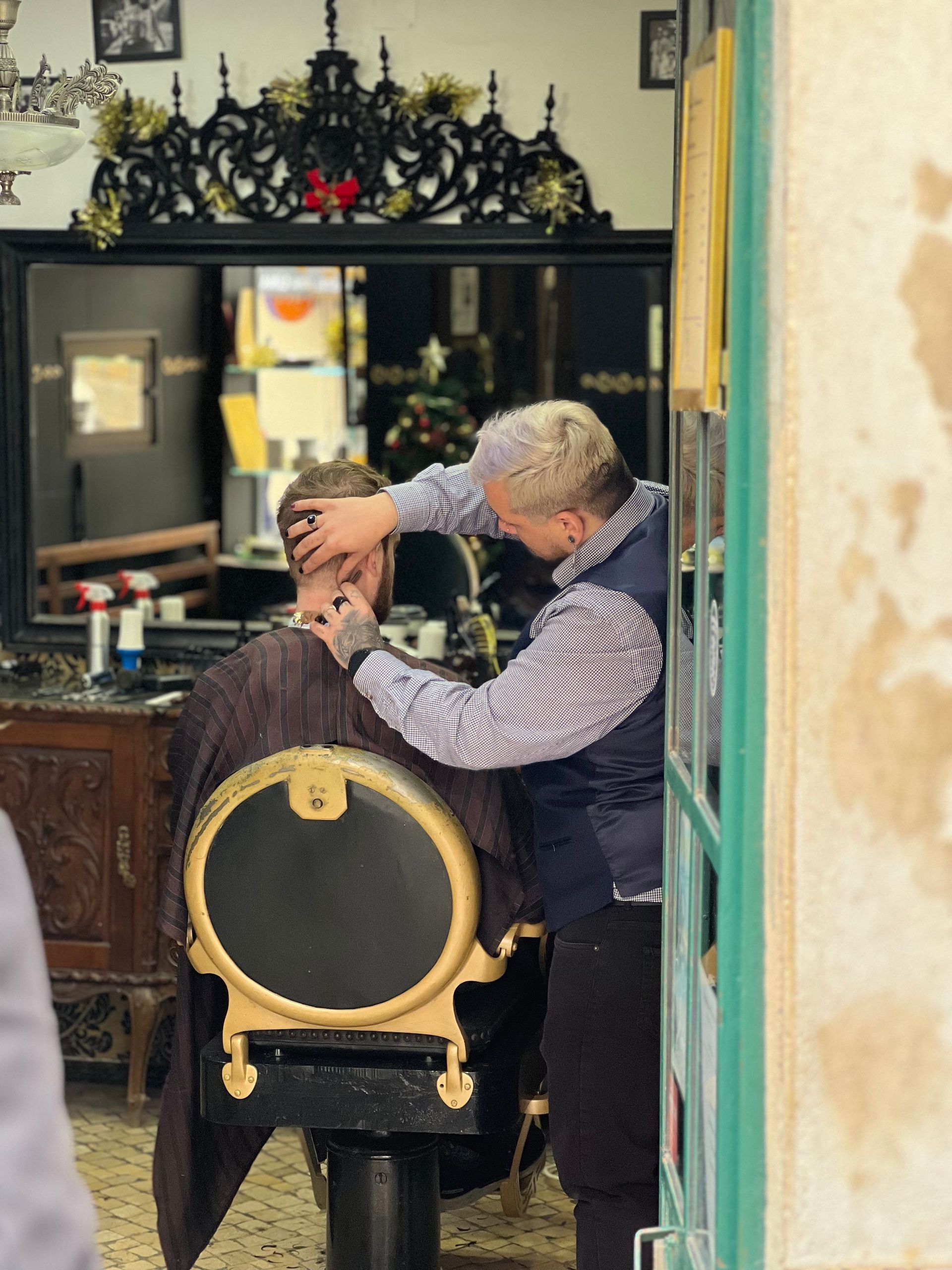Barber trims a client’s hair in a vintage-style salon chair.