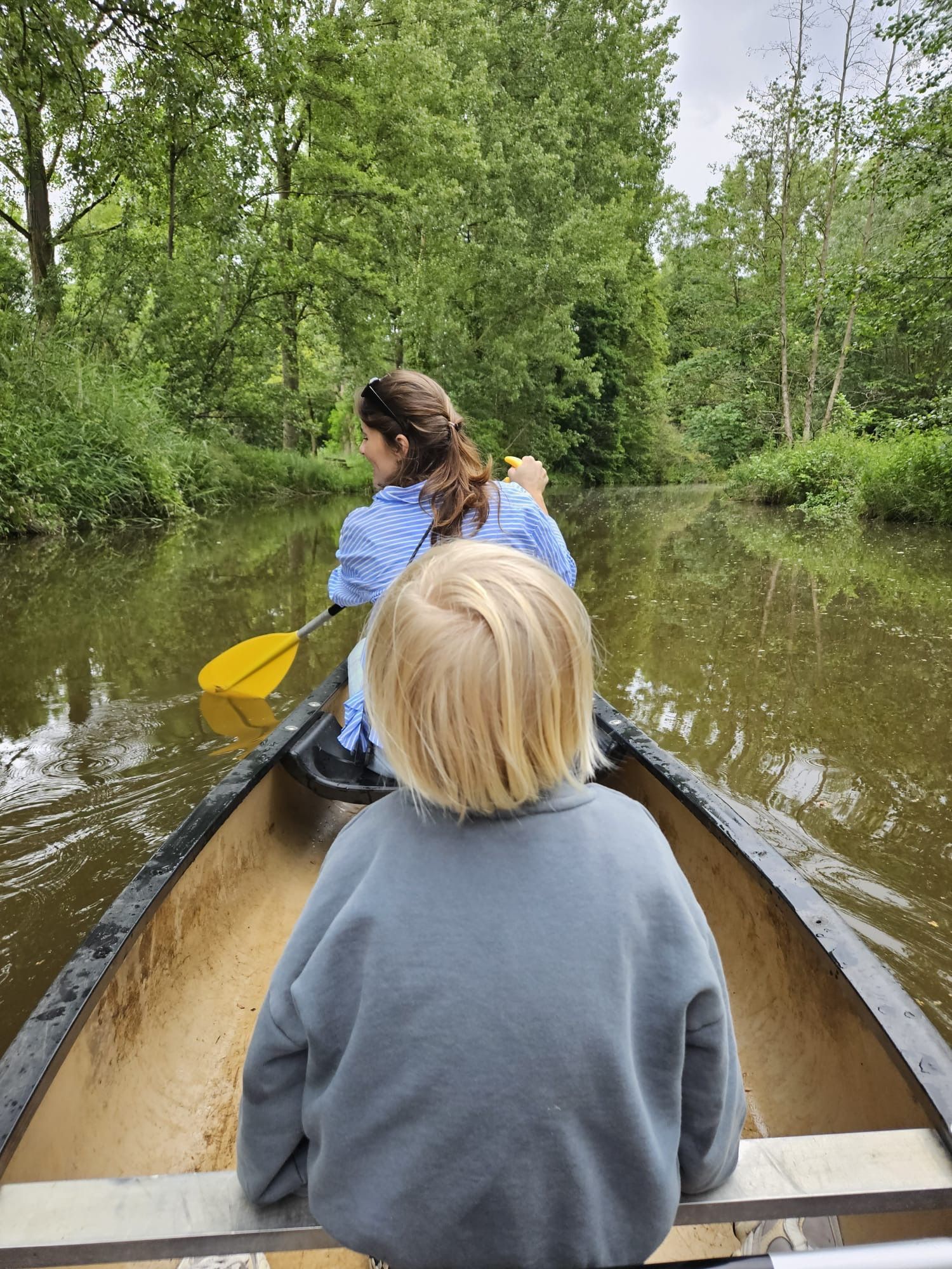 Een vrouw en een kind zitten in een kano op een rivier.