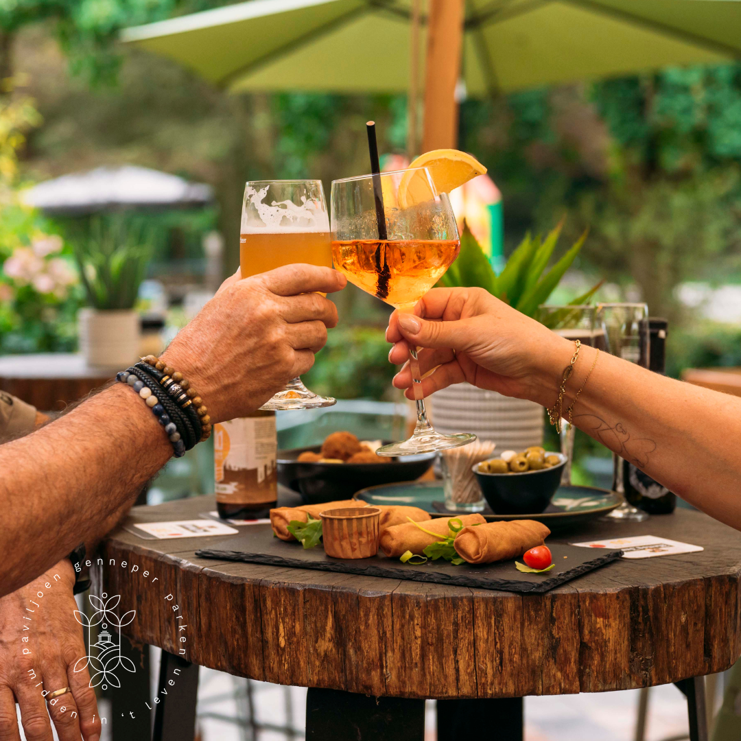 Een man en een vrouw toosten met wijnglazen aan een tafel.