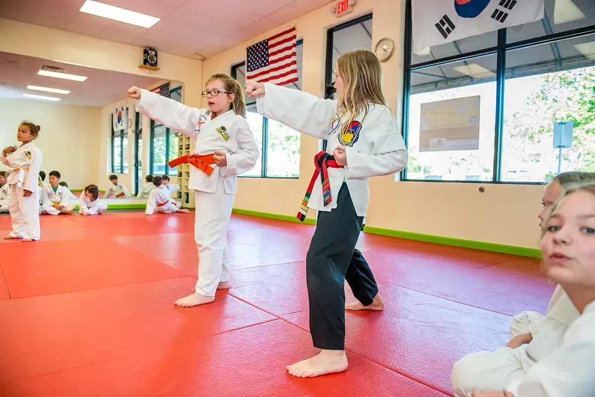Children in karate uniforms practice martial arts in a dojo