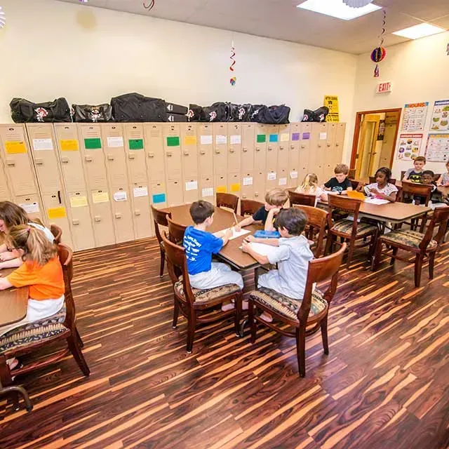 Classroom with students at desks, lockers along the wall, and decorative hanging ornaments