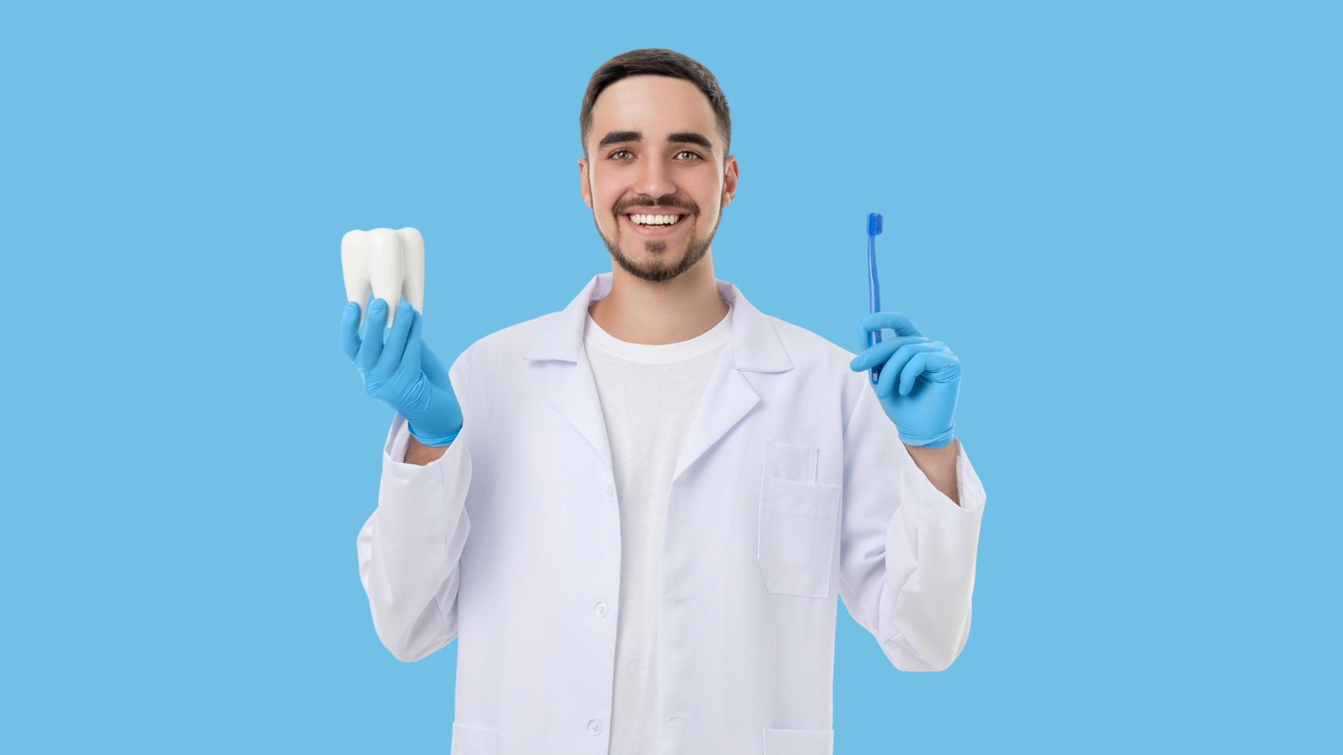 Dentist in white coat holding a tooth model and dental tool on a blue background