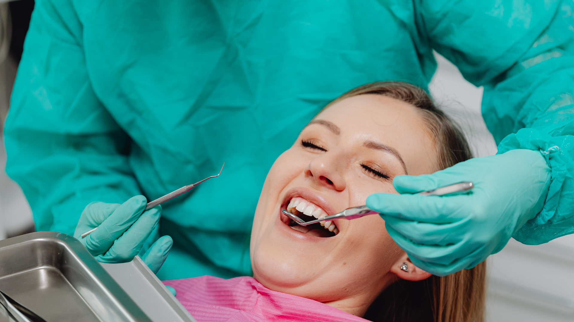 Dentist using tools to work on a smiling patient in a dental chair