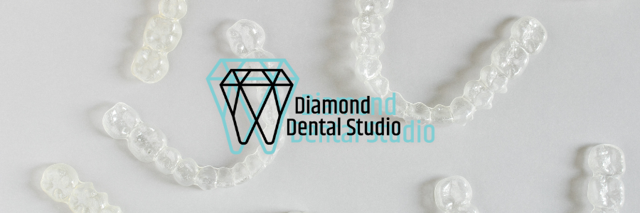 Clear aligners scattered on a white surface, a diamond logo with 