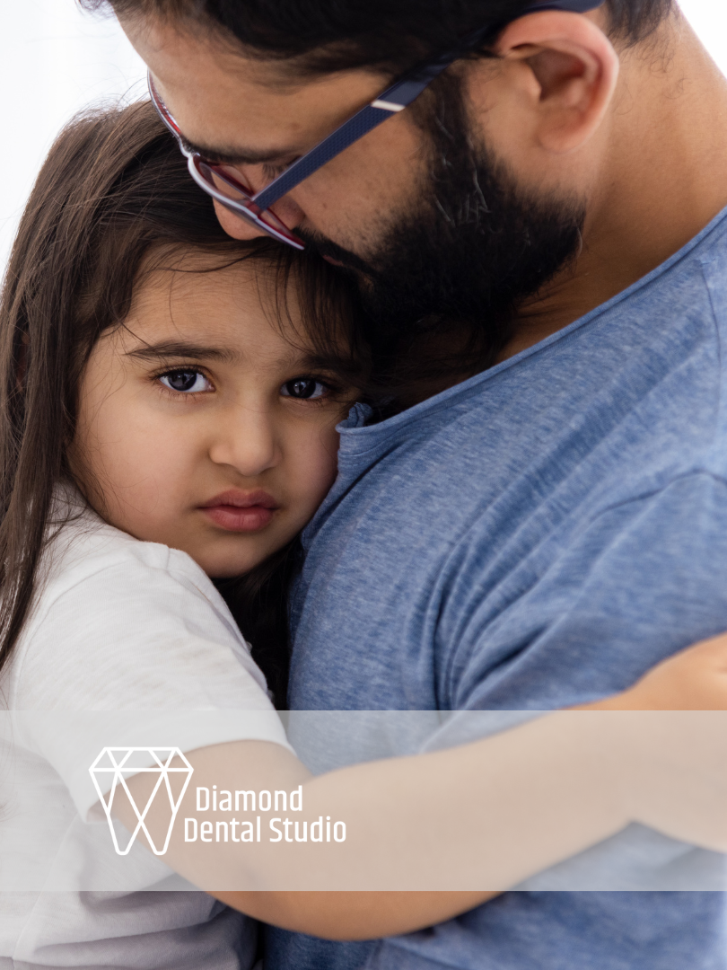 Father hugging a young girl, both looking at the camera with concerned expressions.