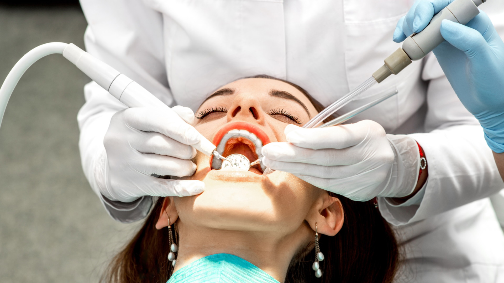 Dentist examining a patient's mouth with tools in a clinic.