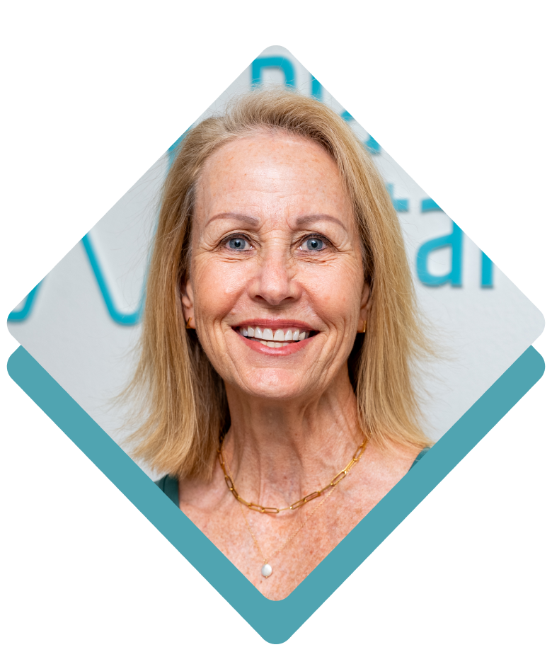 Woman with blonde hair smiling, wearing a gold necklace, in front of a white and teal background.