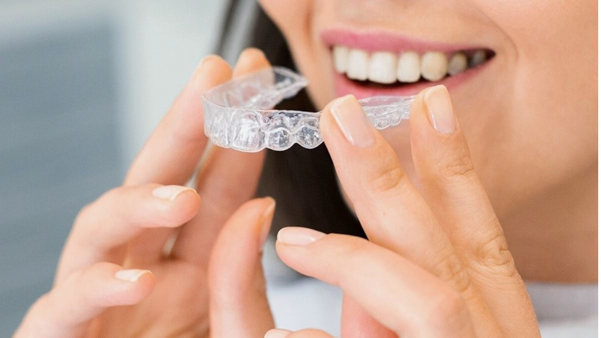 Invisalign aligner next to a model of teeth, resting on a black case.