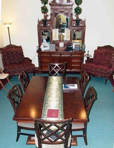 Formal dining room with dark wood furniture, ornate mirror, and upholstered chairs.