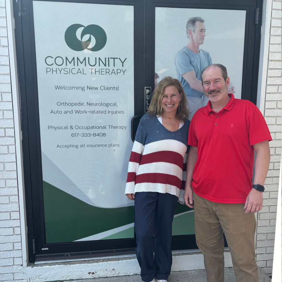 Two people standing outside Community Physical Therapy office door