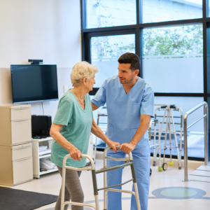 Healthcare worker helping a patient walk with a walker in a bright clinic room