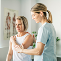 Physical therapist assisting a patient with shoulder exercises in a clinic room