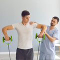 Physical therapist guiding a man using green resistance bands during arm exercise.