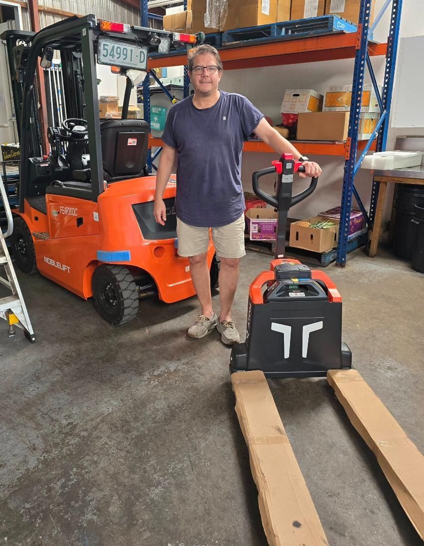 Man Standing Between Orange Forklift — A1 Forklifts In Yamba, NSW