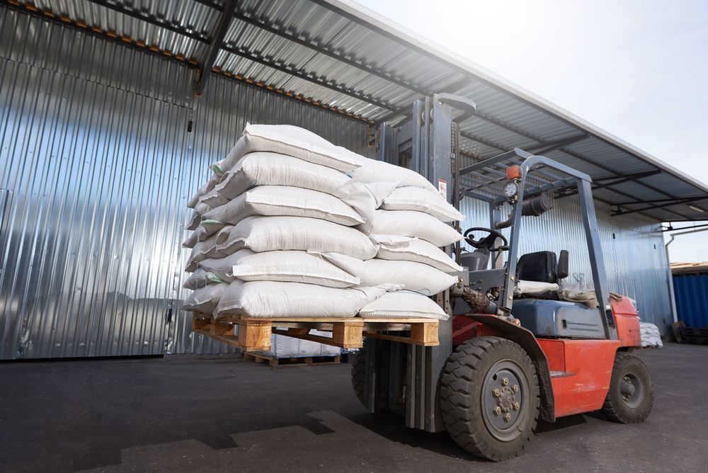 Red Forklift Carrying a Pallet of Stacked White Bags — A1 Forklifts In Kempsey, NSW
