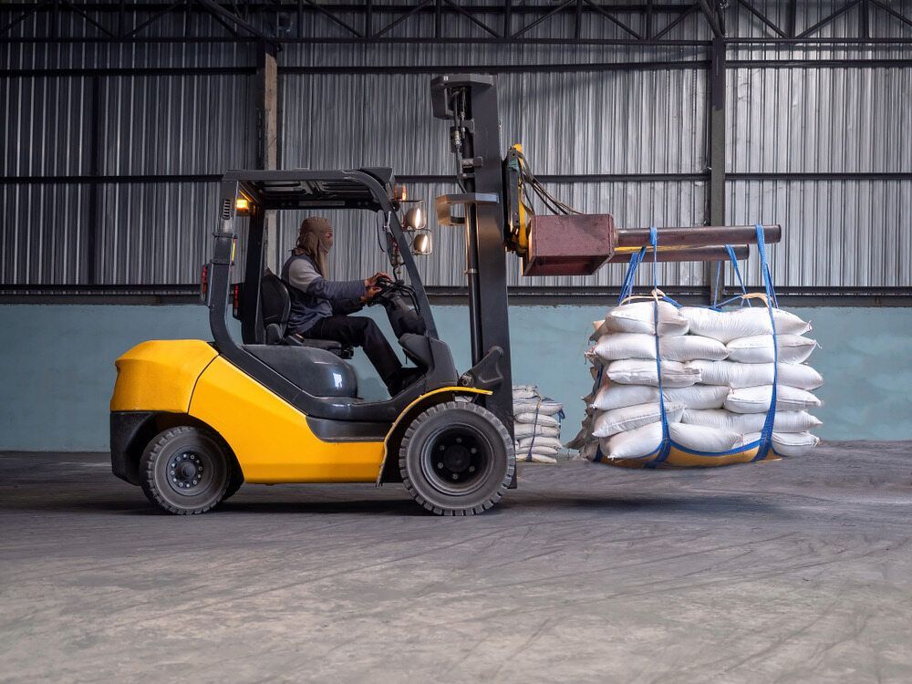 Yellow Forklift Transporting Bags of Material Inside a Warehouse — A1 Forklifts In Coffs Harbour, NSW