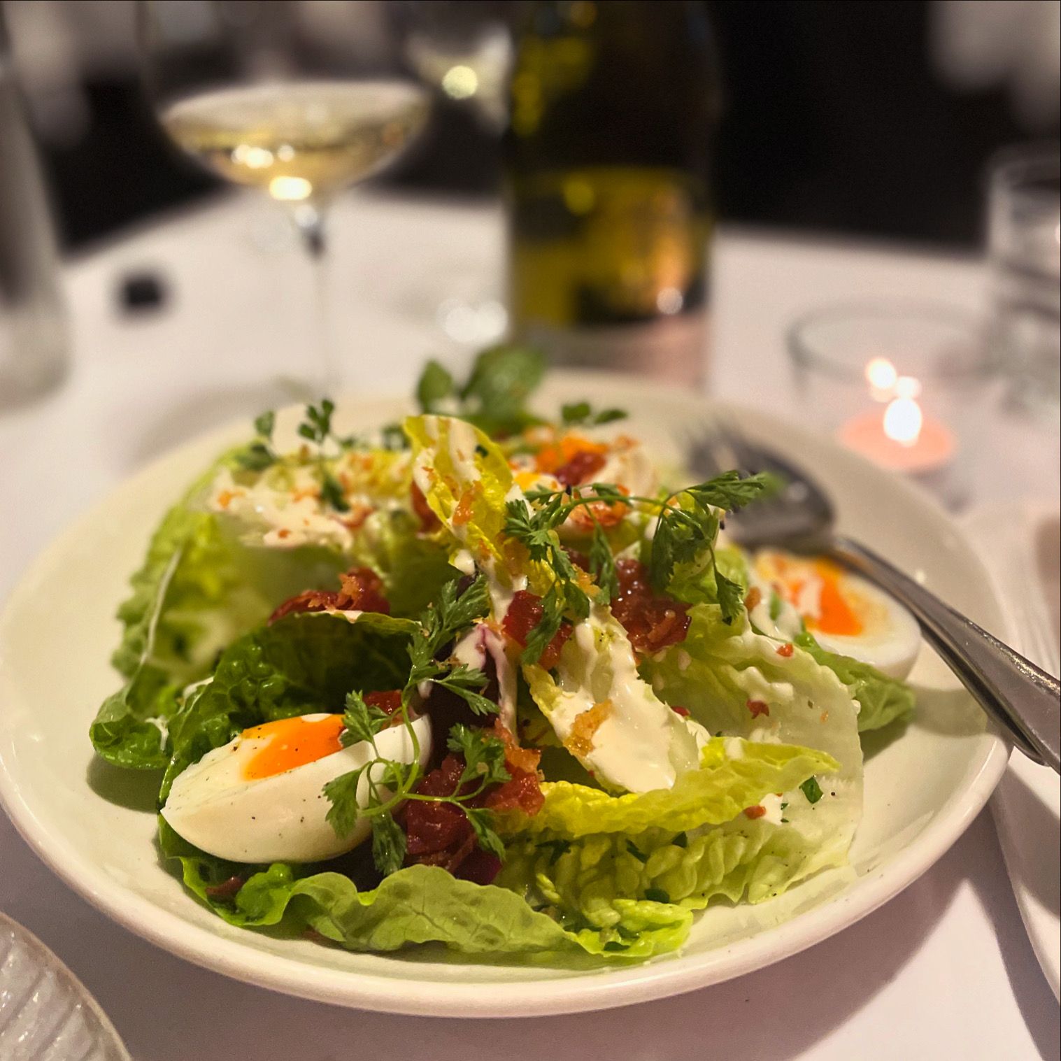 A plate with a salad and a glass of white wine  — Onesta Cucina in Bowral, NSW
