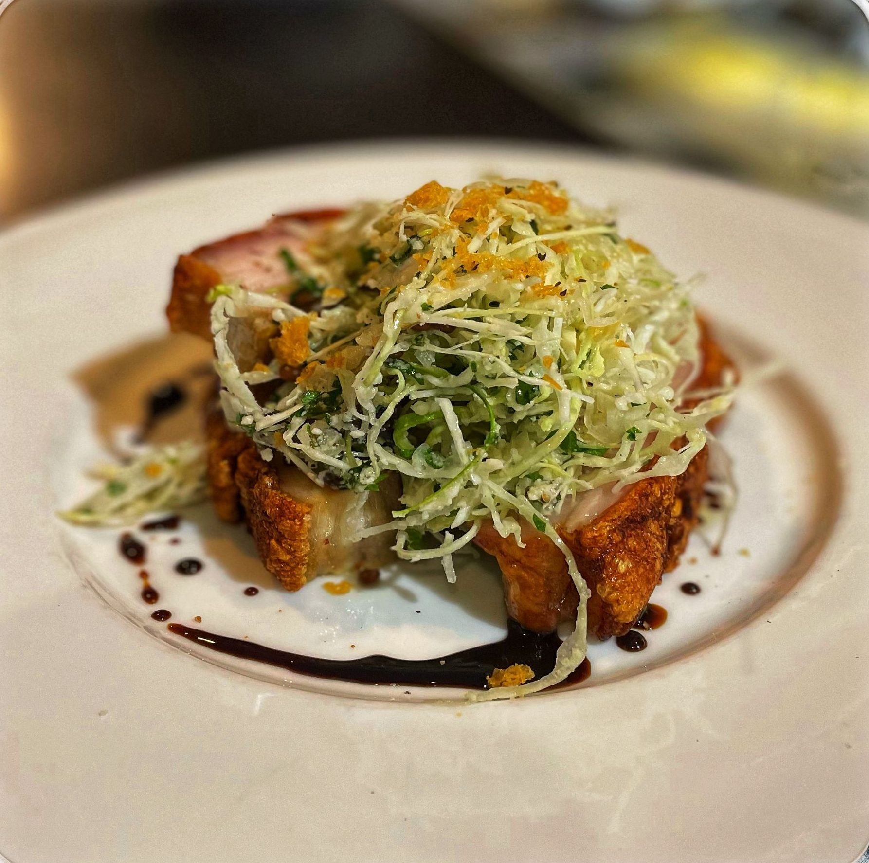 A white plate with pork belly and salad — Onesta Cucina in Bowral, NSW